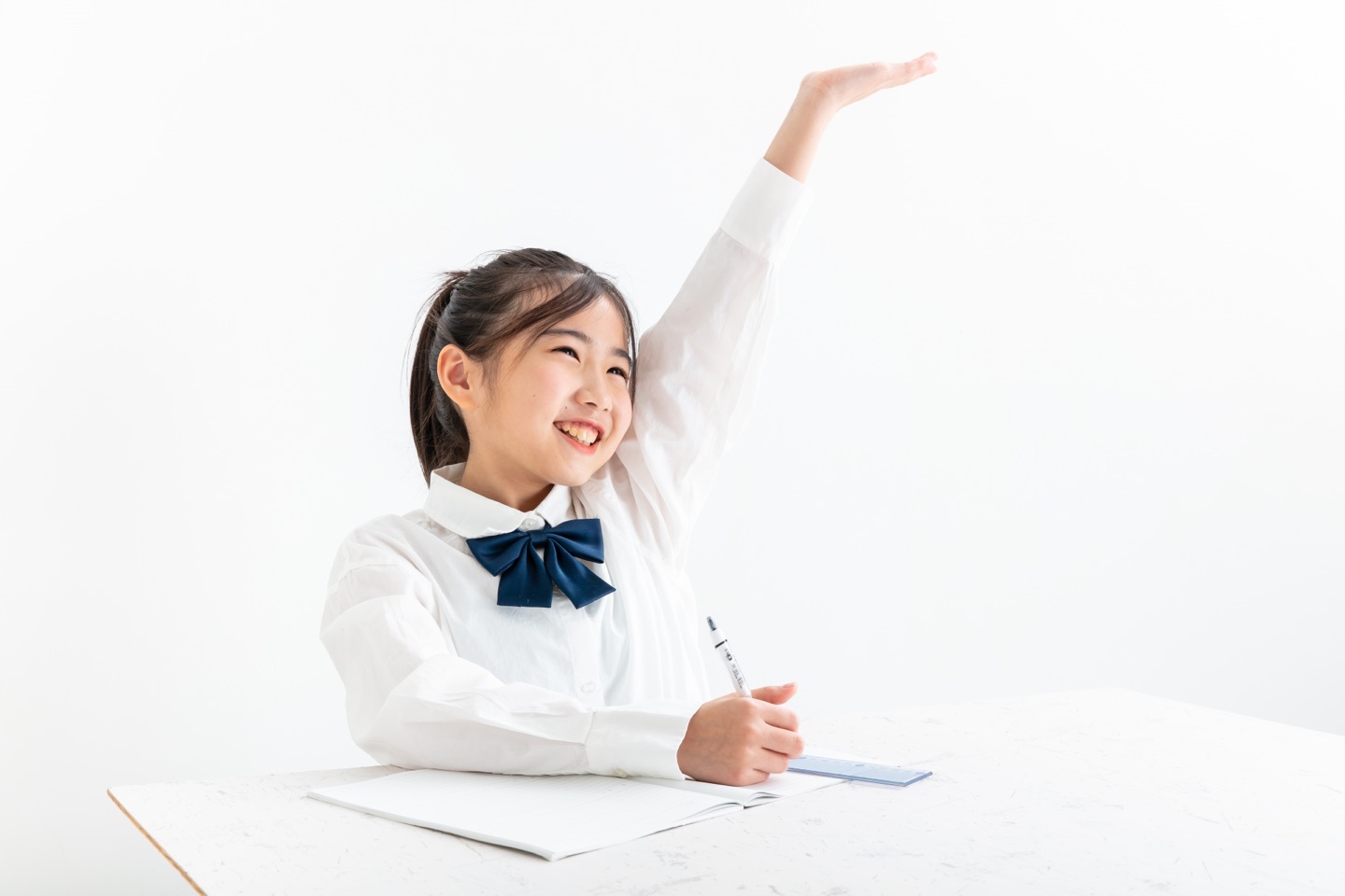 授業で元気よく手を挙げる小学生